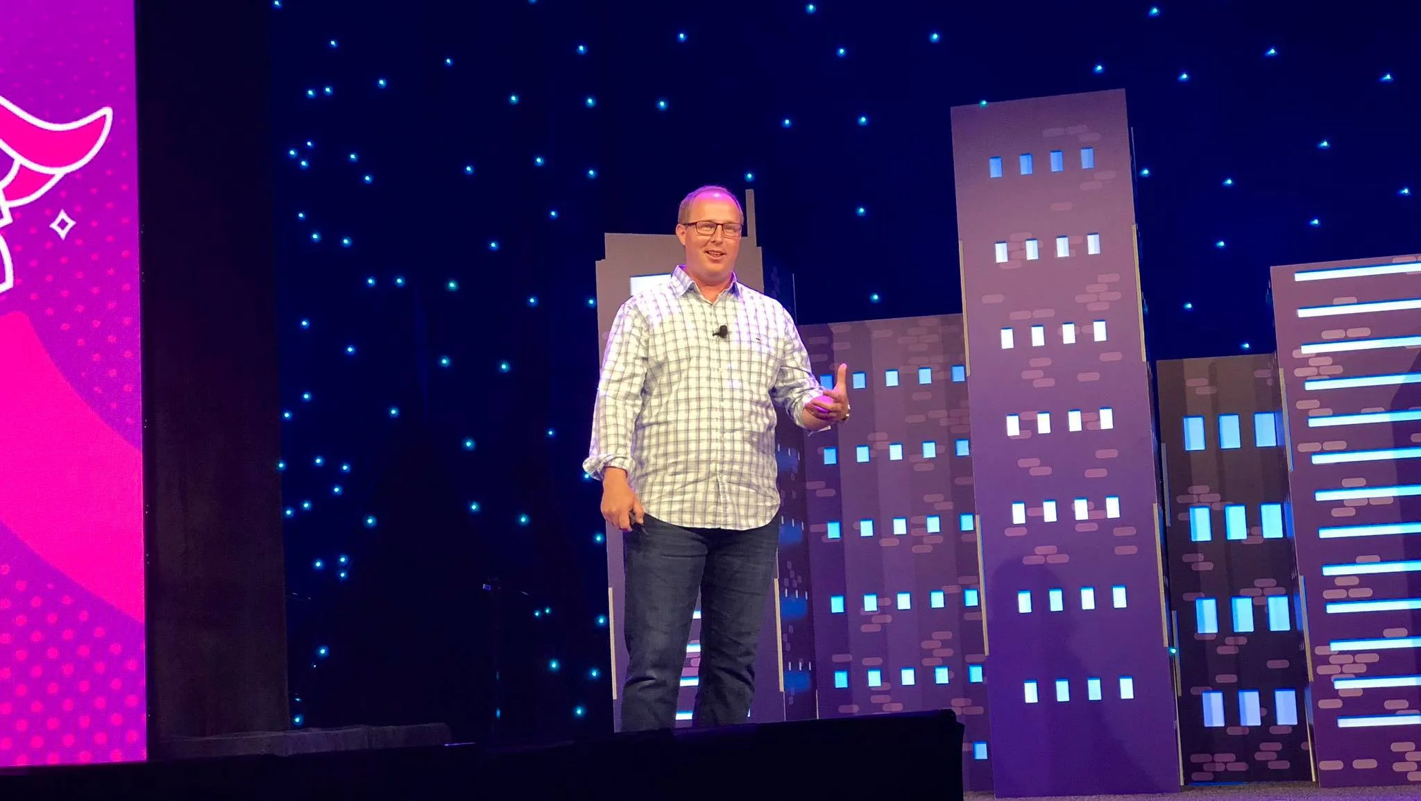 Russ Jones pausing on the MozCon stage, the Space Needle rendered in blue light on the skyline backdrop behind him.